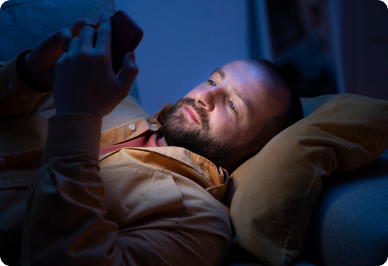 Personne allongée tenant un téléphone